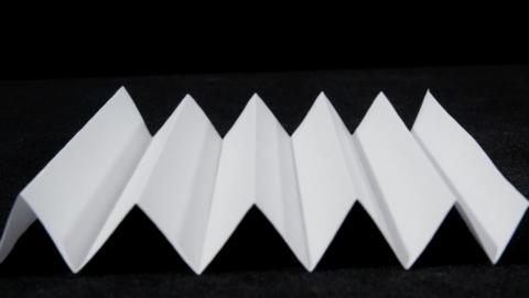 <p>小芳观察到快递包装用的纸板箱都有瓦楞状结构，如图a所示。于是她把A4纸折成了瓦楞状，并如图(b)所示进行了受力测试。小芳发现，当A4纸的形状改变以后，其</p>