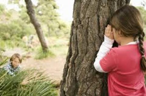 <p>The little girl is ______ behind a tree.</p>